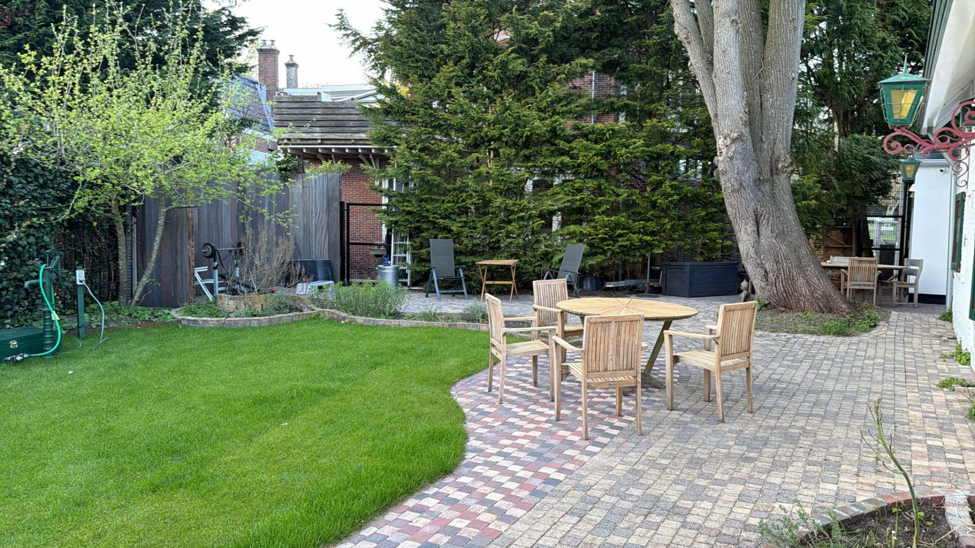 Zorgvuldig aangelegde tuin met gazon, borders en bestrating